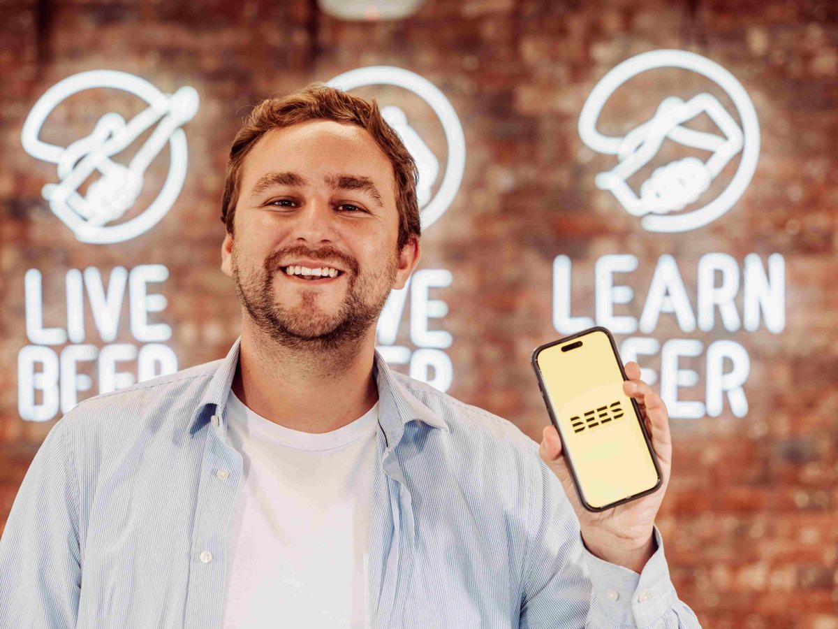 Fabio Macedo, smiling, holding up a phone showing the BEES app